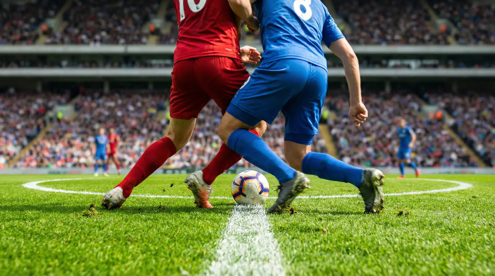 Dos equipos de fútbol disputando un balón dividido en el centro del campo sobre césped verde