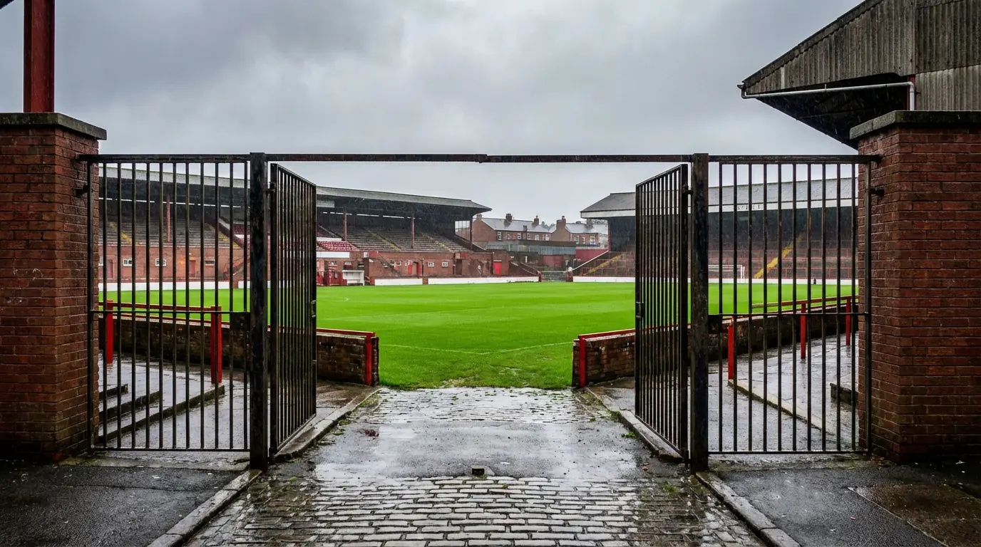 Estadio de fútbol inglés con césped verde intenso bajo un cielo nublado típico de Inglaterra