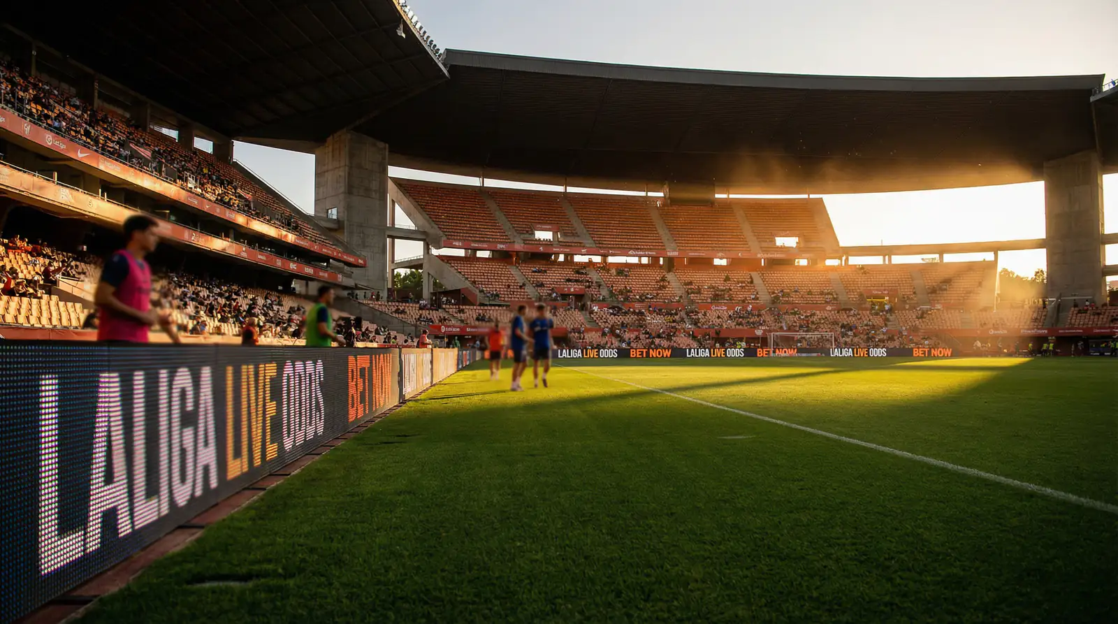 Estadio de fútbol de LaLiga con tablero de cuotas iluminado al atardecer